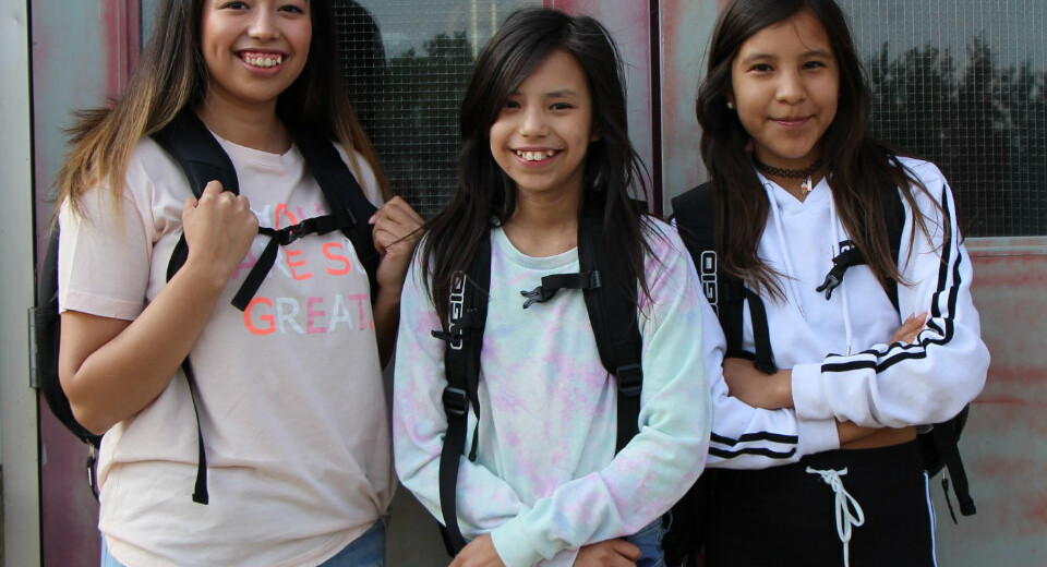 students standing outside building with backpacks