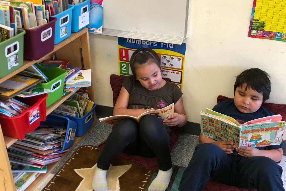 students sitting on ground in classroom reading